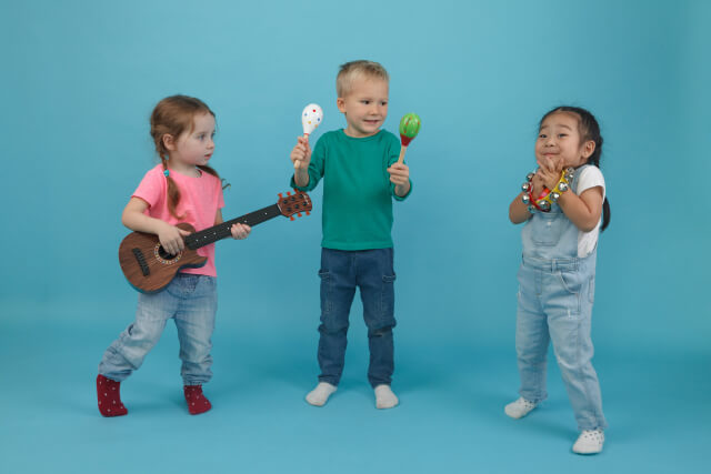 マラカス、タンバリン、ギターのおもちゃで遊んでいる子どもたち。