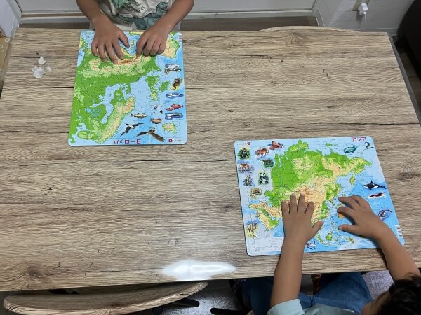 男の子２人がアジア地図とヨーロッパ地図のパズルに挑戦しています。