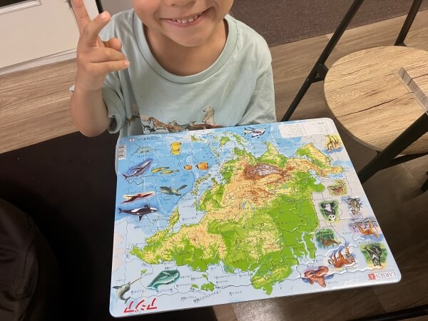 アジア地図のパズルが完成して、にっこり笑う男の子。