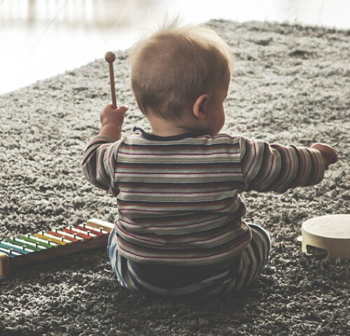 赤ちゃんがタンバリンと鉄琴で遊んでいます。