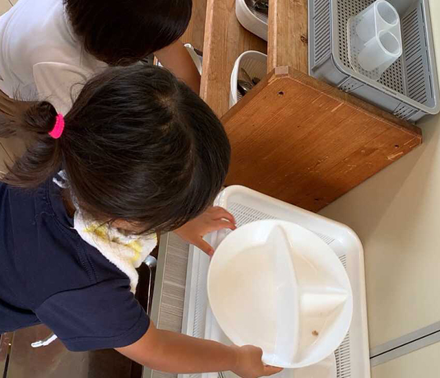 洗った食器を棚に片付けている子どもたち。