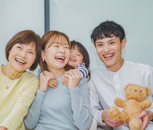 楽しそうに笑う、おばあちゃんとおかあさんに抱き着いている女の子、くまのぬいぐるみを持ったお父さん
