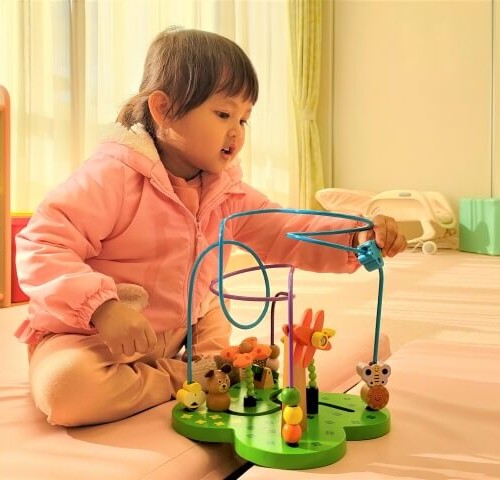 ピンクの服を着た女の子がビーズコースターで遊ぶ様子