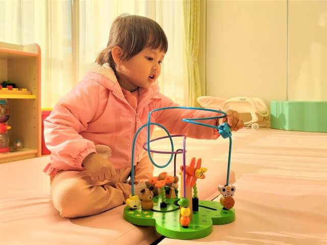 ピンクの服を着た女の子がビーズコースターで遊ぶ様子